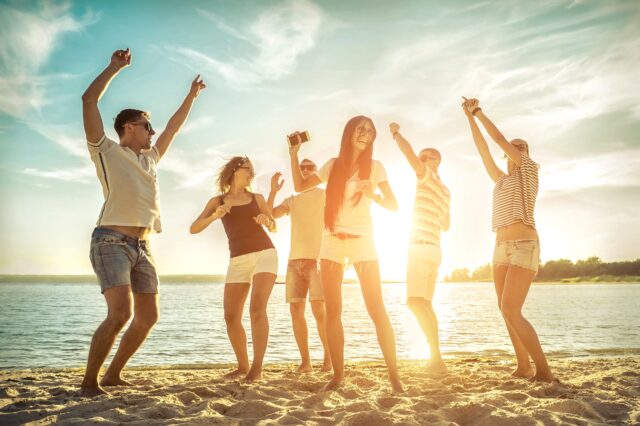 Group of happy people on beach dancing