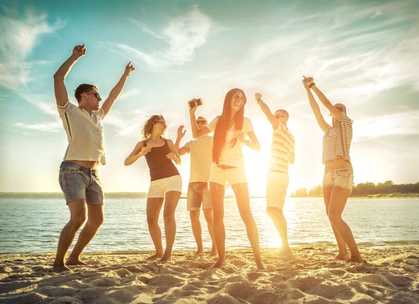 Group of happy people on beach dancing